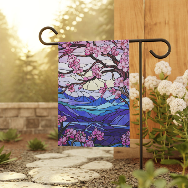 Decorative garden flag with cherry blossom design on a stand outdoors.