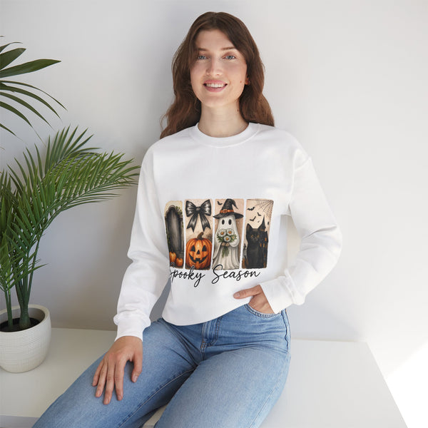 Woman wearing a white sweatshirt with Halloween-themed design sitting on a white surface.