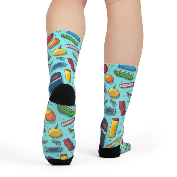 Colorful socks with fruit and book pattern worn by a person on a white background