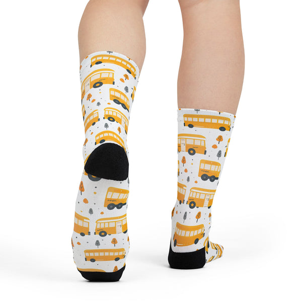 Socks with yellow school bus pattern worn by a person on a white background