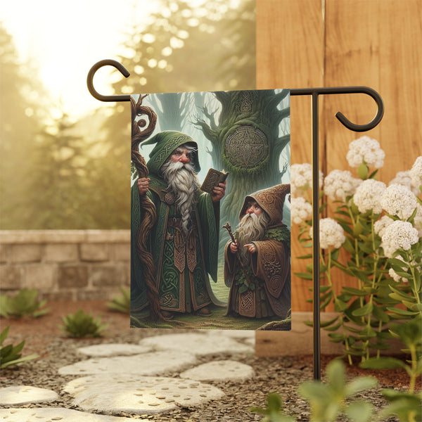 Decorative garden flag with two wizards in a forest setting, held by a stand outdoors.