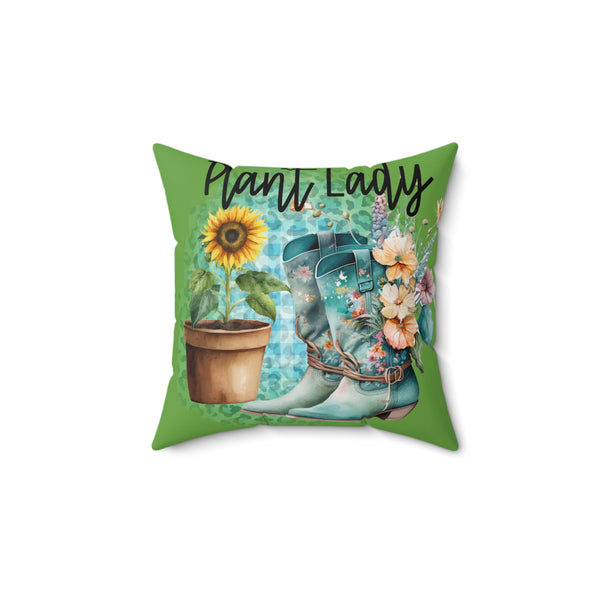 Decorative pillow with gardening-themed design featuring boots, sunflower, and flowers on a green background.