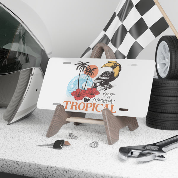 Decorative license plate with tropical design on a stand, surrounded by car parts and tools.