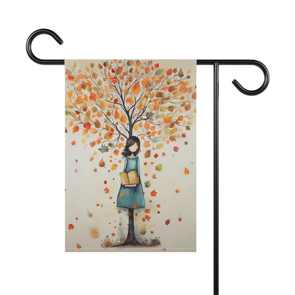 Garden flag with a design of a woman holding books under an autumn tree on a white background.
