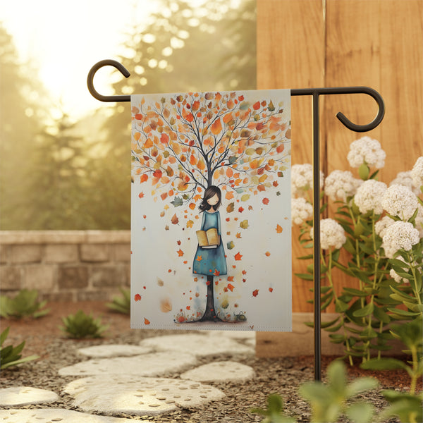Decorative garden flag with a tree and person design on a stand outdoors.