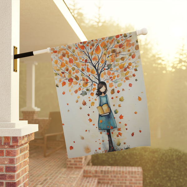 Decorative flag with a woman and autumn tree design on a porch.