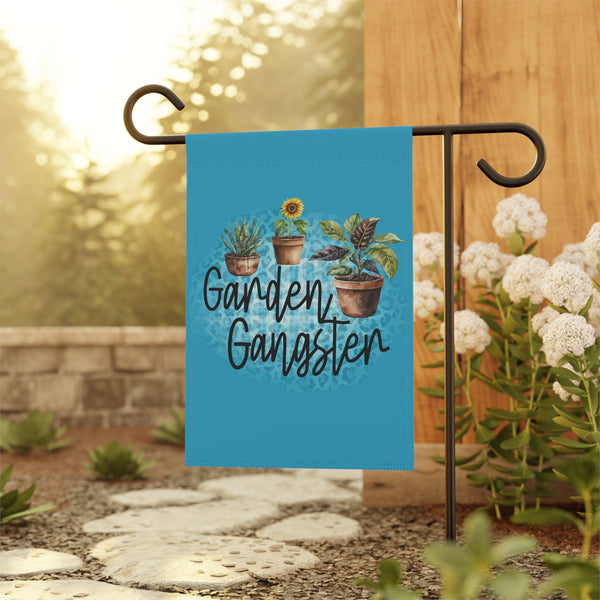 Garden-themed decorative flag with plants and 'Garden Gangster' text on a stand outdoors.