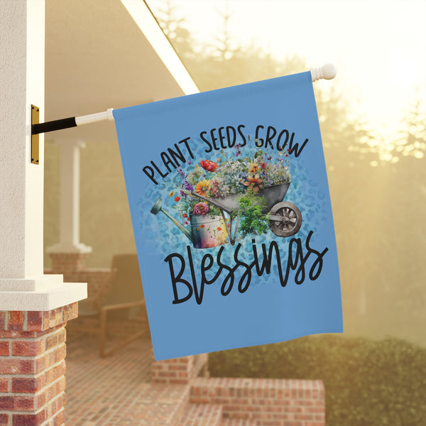 Decorative garden flag with 'Plant Seeds, Grow Blessings' text and garden imagery on a blue background, hanging outdoors.
