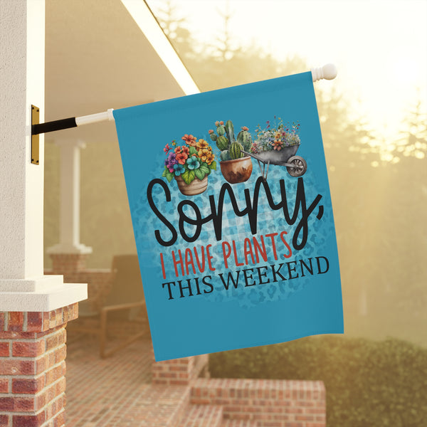 Decorative garden flag with plants and text 'Sorry, I have plants this weekend' on a porch.