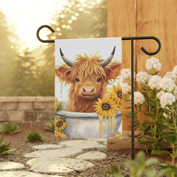 Decorative garden flag with a highland cow design, hanging outdoors.