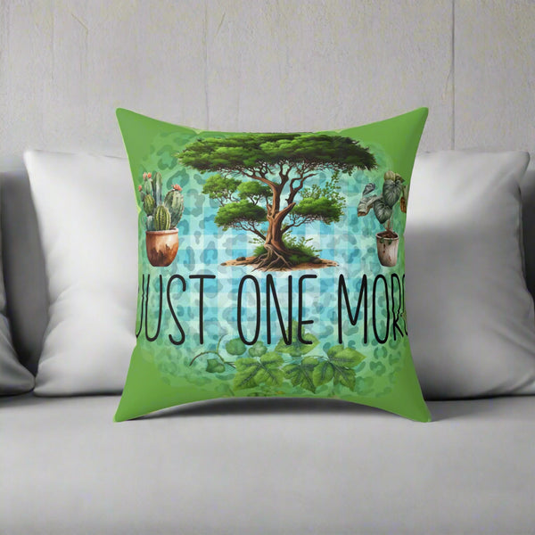 Decorative pillow with a tree and plants design and text 'JUST ONE MORE' on a green background.