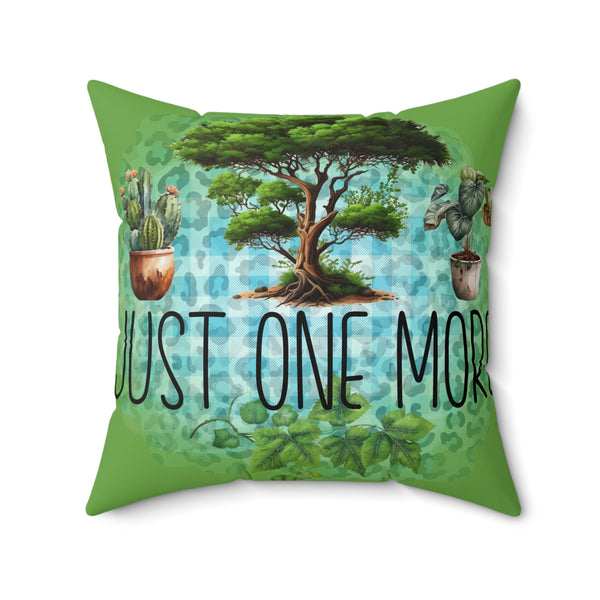 Decorative pillow with a tree and plants design and 'Just One More' text on a green background.