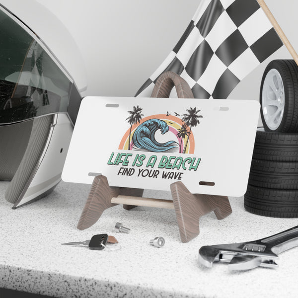 License plate with beach-themed design and text, placed on a stand with tools and car parts in the background.