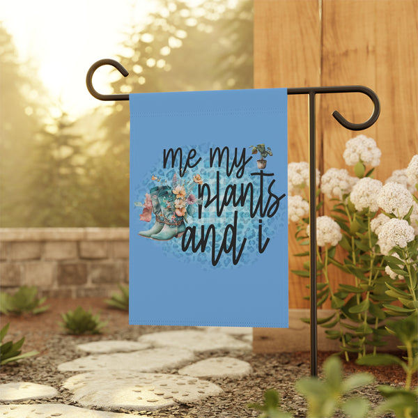 Decorative garden flag with 'me, my plants, and I' text and boots design on a stand outdoors.
