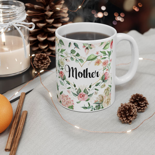 White mug with floral design and 'Mother' text, surrounded by decorative items on a table.