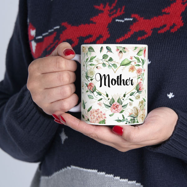 Person holding a mug with floral design and 'Mother' text, wearing a sweater with deer pattern.