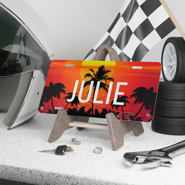 Personalized license plate with palm tree design and name 'Julie' on a counter with tools and tires.