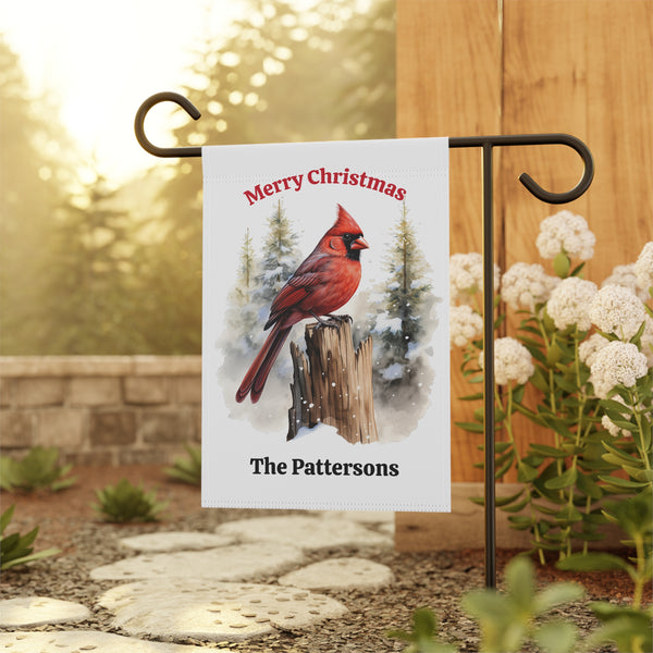 Garden flag with a red cardinal and 'Merry Christmas The Pattersons' text, displayed outdoors.