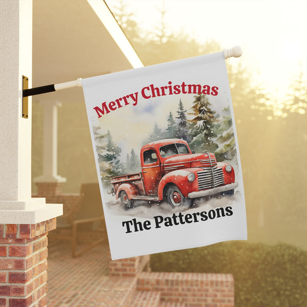 Decorative Christmas flag with a red truck and 'Merry Christmas The Pattersons' text, hanging outside a house.