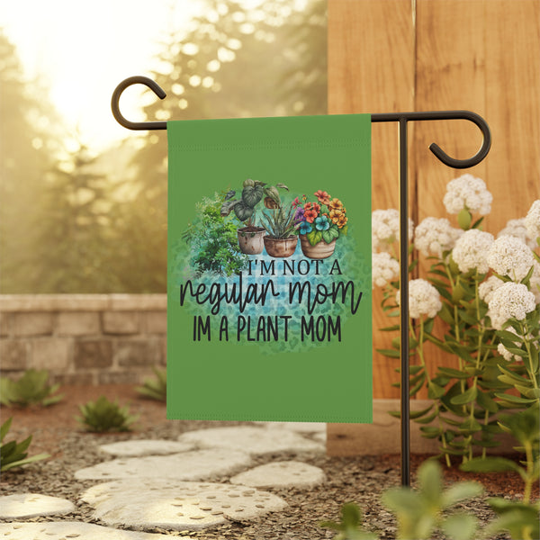Garden flag with plant-themed design and text, hanging outdoors.
