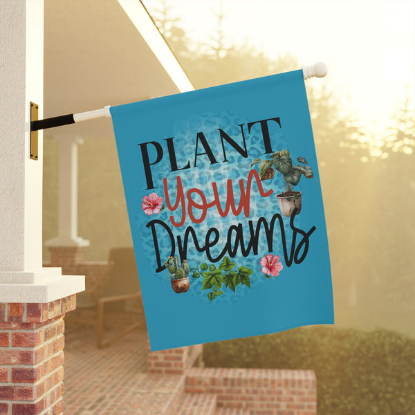 Decorative garden flag with 'Plant Your Dreams' text and plant illustrations on a porch background.