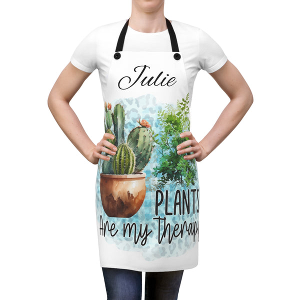 Person wearing a white apron with plant-themed design and text