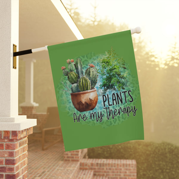 Decorative garden flag with cacti design and 'Plants are my therapy' text, hanging outdoors.