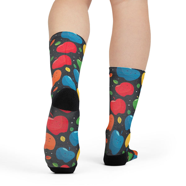 Colorful socks with apple pattern worn by a person on a white background