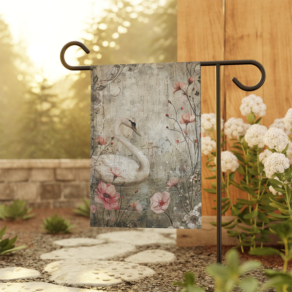 Decorative garden flag with swan and floral design on a stand outdoors.