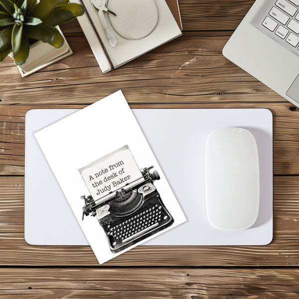 Note from the desk of Judy Baker with typewriter illustration on a desk setup.