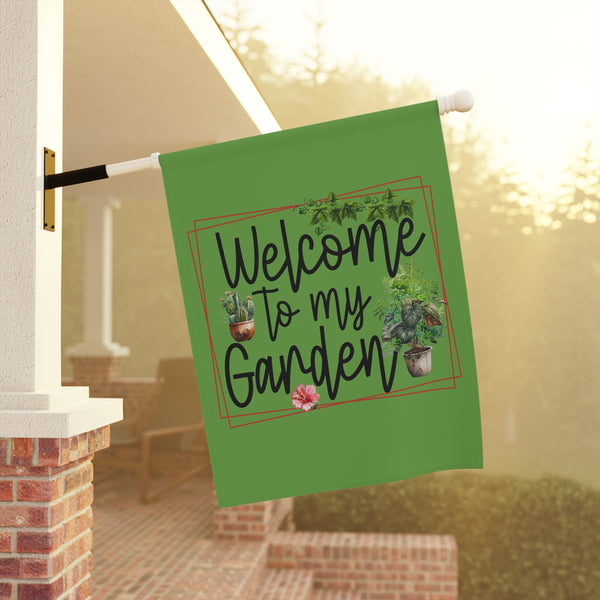 Green garden flag with 'Welcome to my Garden' text and plant illustrations, hanging outdoors.