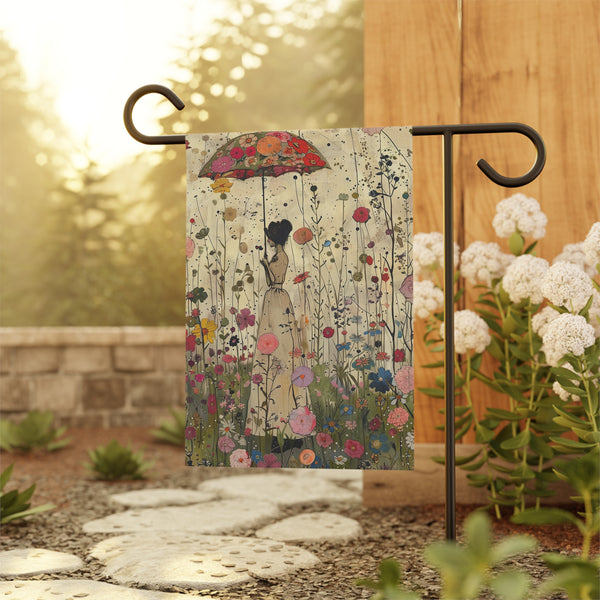 Decorative garden flag with a floral design featuring a woman holding an umbrella, hanging on a stand outdoors.