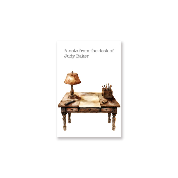 Note card with illustration of a desk, lamp, and stationery on a white background