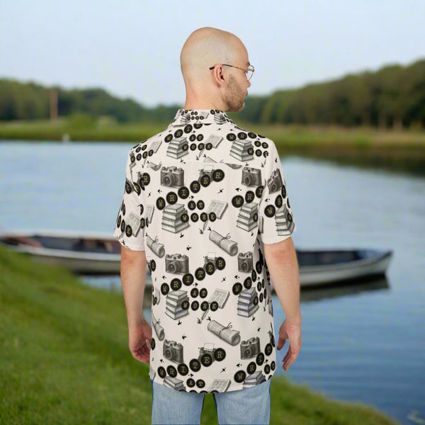 Man wearing a patterned shirt with cameras and books on a white background