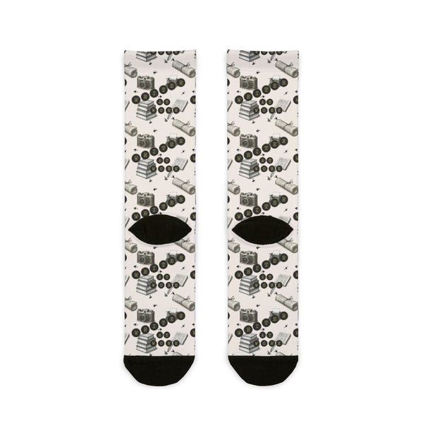Pair of socks with a pattern of black shoes and eye shapes on a white background