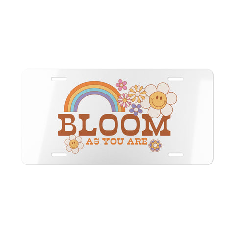 Decorative license plate with rainbow, flowers, and 'Bloom as You Are' text on a white background