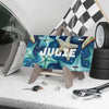 License plate with starfish design and 'JULIE' text, placed on a stand with car accessories in the background.