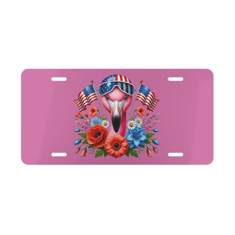 Pink license plate with a flamingo wearing sunglasses and American flags, surrounded by flowers on a white background.