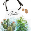 Apron with cactus design and 'Julie' printed on it, accompanied by cookies.